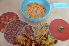 there are four different types of food in the bowls on the table, including pasta and beans