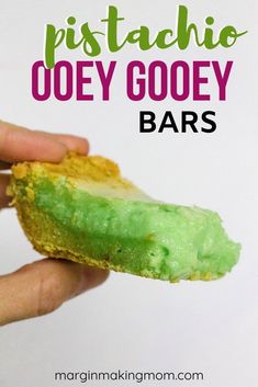 a hand holding a piece of food with green icing on it and the words pistachio ooey gooey bars