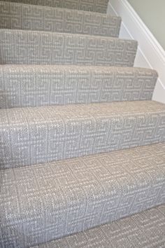 a cat sitting on top of a carpeted stair case