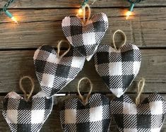 four black and white plaid heart ornaments hanging from string lights