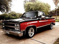 a red and black truck parked on the side of a road in front of a house