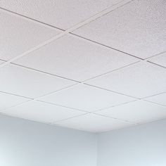 an empty room with white walls and ceiling tiles