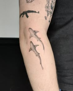 a man's arm with tattoos on it and two dolphins in the water behind him