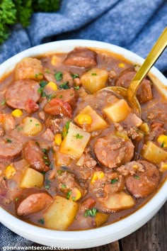 a white bowl filled with stew and potatoes on top of a wooden table next to a blue towel