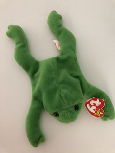 a green stuffed animal laying on top of a white table