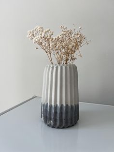 a white and grey vase with flowers in it