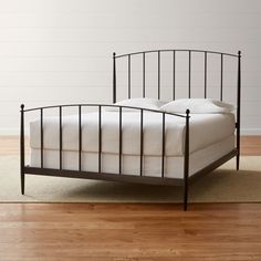 an iron bed frame with white sheets and pillows