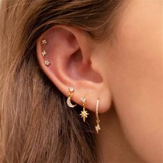 a woman's ear is adorned with gold stars and moon earrings