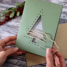 someone is making a christmas tree card with twine