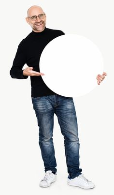 a man in black shirt and jeans holding up a white board with one hand on his hip