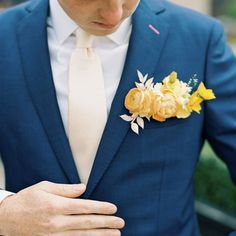 a man wearing a blue suit and white shirt with yellow flowers on his lapel