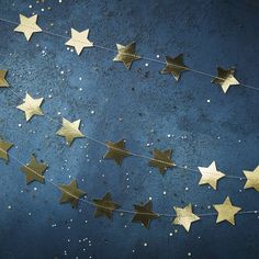 gold stars are hanging on a string against a blue background