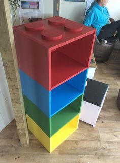 a multicolored book shelf sitting on top of a hard wood floor next to a chair