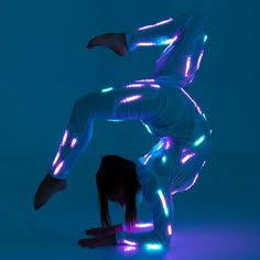 a woman in white is doing a handstand with neon lights on her body