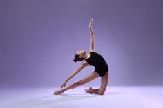 a woman in black leotard doing a dance pose against a purple background with her arms stretched out