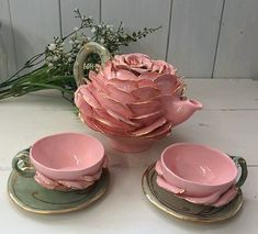 pink flowers are in the vase next to two cups and saucers