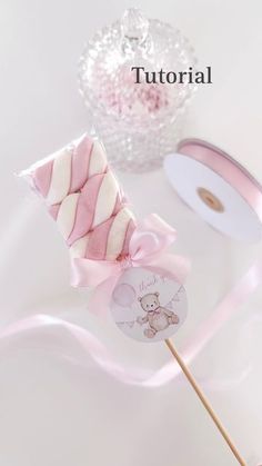 a pink and white striped lollipop on a stick next to a cupcake