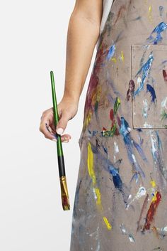 a person holding a paintbrush in their left hand and wearing an apron on the other