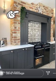 a kitchen with black cabinets and white counter tops, an oven and stove top in front of a brick wall