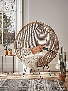 a living room with a hanging chair and potted plants on the floor next to a window