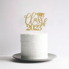 a white cake topped with a gold graduation cake topper