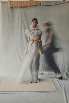 a woman is standing in front of a white backdrop