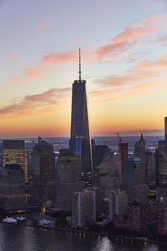 the skyline of new york city at sunset with one world trade center in the foreground