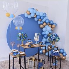 blue and gold party decorations with balloons on the wall, table set up for an event