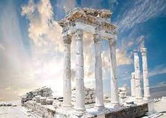 an ancient structure with columns and pillars in the foreground, against a blue sky