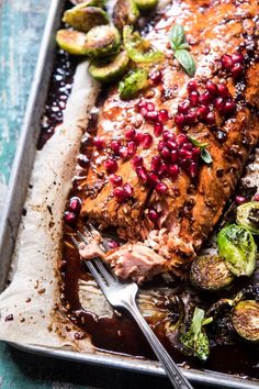 salmon with pomegranates and brussel sprouts on a baking sheet