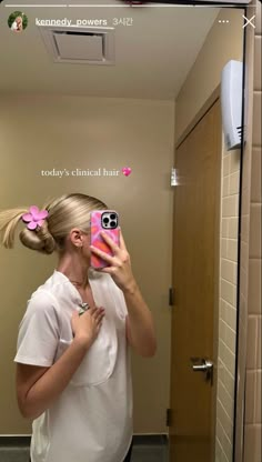 a woman taking a selfie in front of a mirror with her hair pulled into a pony tail