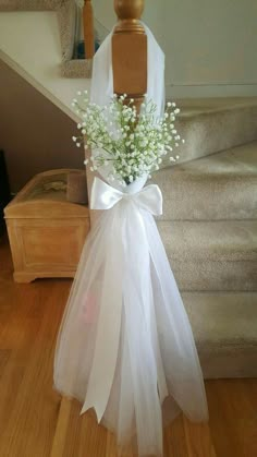 a bouquet of baby's breath sits on a mannequin in front of stairs