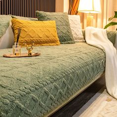 a bed with green bedspread and two yellow pillows on top of it next to a lamp