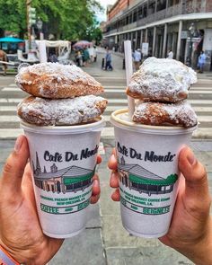 two people holding up cups with donuts on top of each other in front of a crosswalk