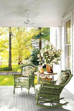 a porch with wicker furniture and flowers on the table