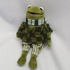 a stuffed frog is dressed in green and white checkered clothing with eyes wide open