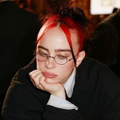 a woman with red hair and glasses sitting at a table