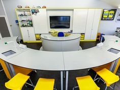 an office with yellow chairs and a flat screen tv on the wall in the center