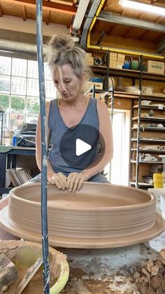 a woman is making a vase out of clay on a potter's wheel in her workshop