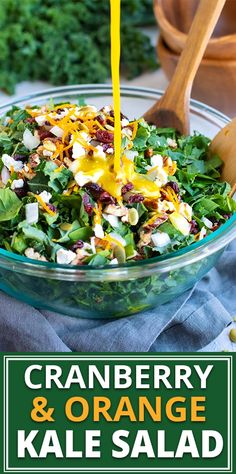 cranberry and orange kale salad in a glass bowl with a wooden spoon