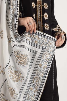 TOP:- Raw SilkBOTTOM:- Raw SilkDUPATTA:- Medium SilkOur delicately handcrafted silk shirt features block print with embroidered accents in gota on the neckline. It is further detailed with block-printed facings and paired with a block, printed dupatta in black, white and gold hues. It is styled with our wide-hem pants for your comfort. Disclaimer: Minor variations in these ensembles are intrinsic to the process of creating handcrafted products and add to their appeal Block Print Dupatta Designs, Block Printed Dupatta, Block Print Dupatta, Hand Block Printed Suits, Zara Shahjahan, Block Printed Suits, Hem Pants, Black White And Gold, Deco Pattern