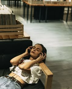 a woman sitting in a chair talking on a cell phone while holding her head to her ear