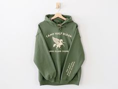 a green hoodie with the words camp half blood printed on it, hanging from a hanger