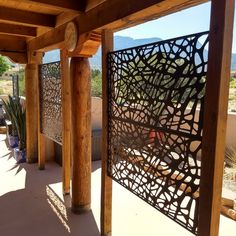 an outdoor area with wooden pillars and metal screens on the outside, along with mountains in the background