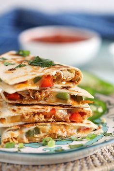 three quesadillas stacked on top of each other with sauce in the background