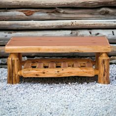 a wooden bench sitting on top of a carpeted floor next to logs and gravel