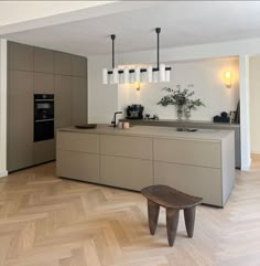 a modern kitchen with an island bench in the middle and wooden flooring on the other side