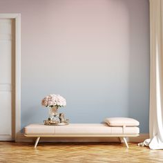 a white bench with flowers on it in front of a blue wall and wooden floor