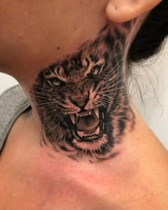 a woman's neck with a tiger tattoo on it