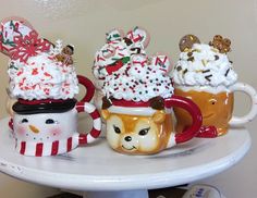 three mugs filled with different kinds of food on top of a white cake plate